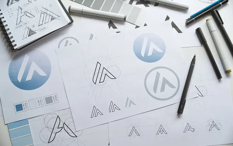 Logo design sketches and concept art in progress with pens, swatches, and paper.
